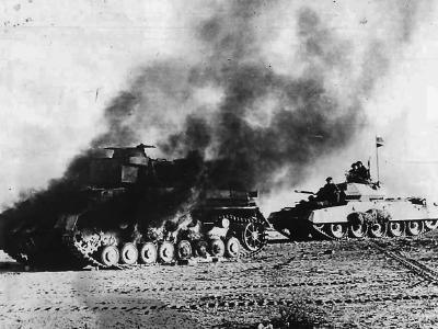 Crusader tank passing a burning Panzer IV during Operation Crusader in Libya 1941