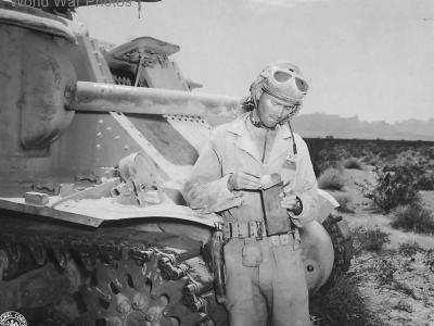 Member of 3rd Armored Division tank crew opens a box of field rations by his M3 ,1943