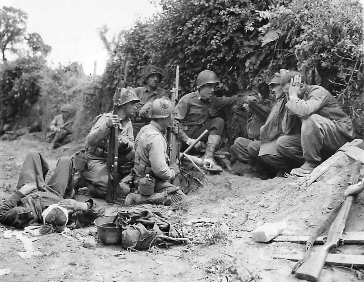 Captured German soldiers shelter with US soldiers at St. Lo July 1944