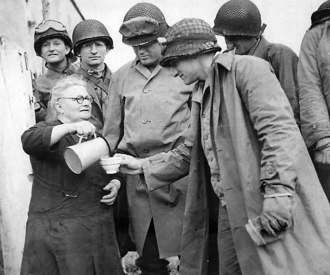 Elderly woman pours milk for US Army soldiers in the Normandy area of France