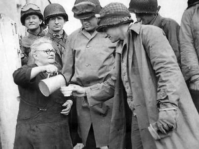 Elderly woman pours milk for US Army soldiers in the Normandy area of France
