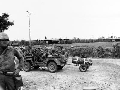 Infantrymen in Jeep get directions from a MP at a Normandy crossroads