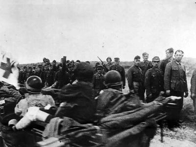 Jeep carrying allied wounded passes Nazi prisoners on Normandy beach