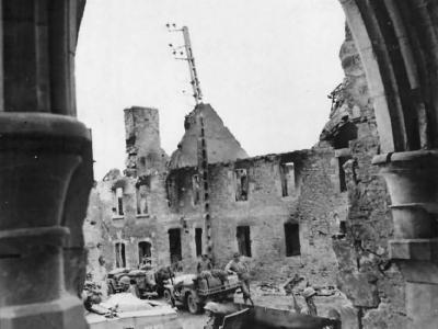 US Army Soldiers and Vehicles Move through St. Giles Normandy France July 1944