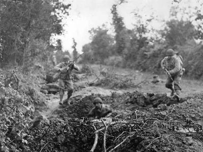 US Infantrymen leap for safety of shell hole in Normandy