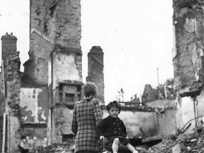 Woman and child on bicycle inspect ruins of Mortain