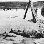 Crossed rifles beside fallen US soldier on D-Day Omaha Beach