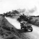Troops pass burning German equipment on road to combat zone Falaise, Summer 1944