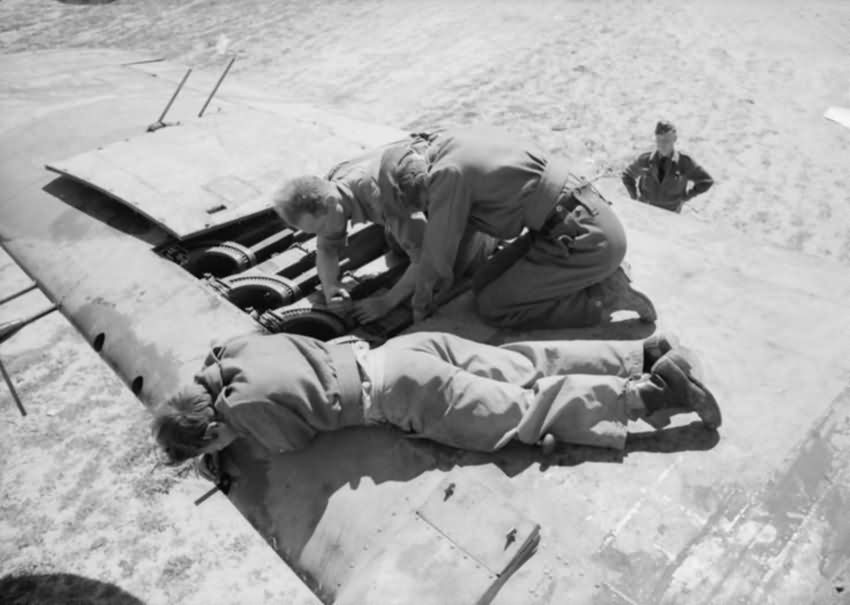 Armourers of No. 89 Squadron RAF installing a 0.303 Browning machine gun in the wing of a Bristol Beaufighter Mk VIF at Castel Benito Libya