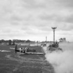Sherman tanks move up past a crash landed Spitfire, for an attack on Tilly-sur-Seulles, Normandy 17 June 1944
