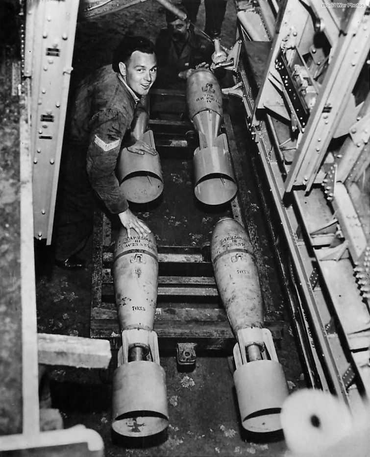 View thru bomb bay as ground crew loads bombs on B-17
