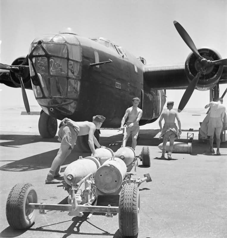 Armourers pull a trolley loaded with 500 lb bombs to a Liberator Mk II of No 159 Squadron RAF at Fayid Egypt