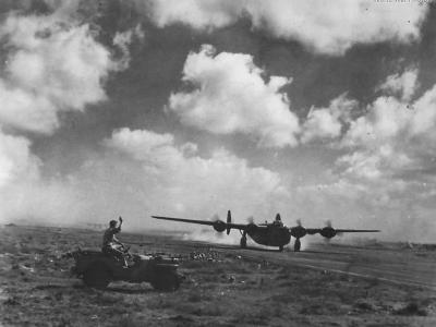 Airman in Jeep Waves to 9th AF B-24 taking off in North Africa