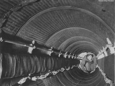 Crewman crawling thru padded fuselage tunnel of B-29