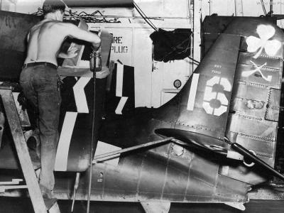 A sailor applies markings to a FM-2 Wildcat of VC-94 USS Shamrock Bay CVE-84