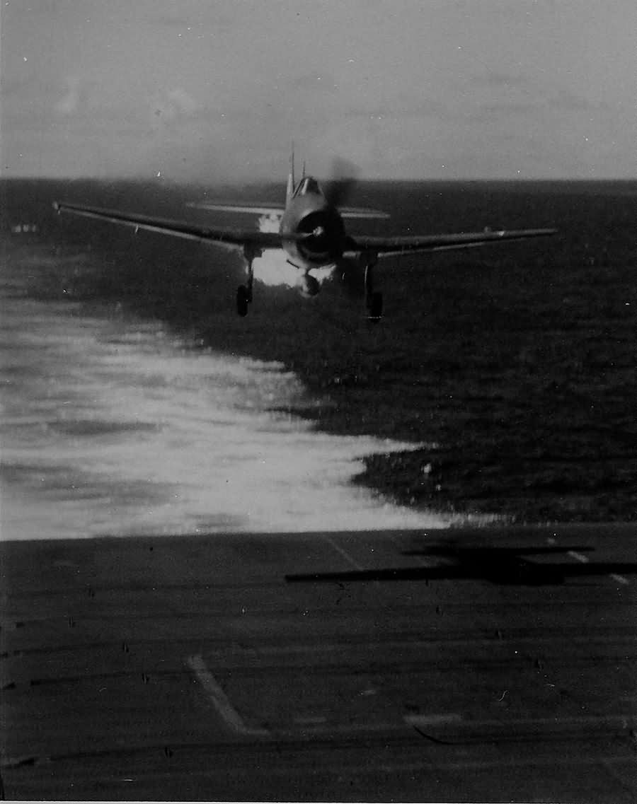 Grumman F6F-3 Hellcat flown by Lieutenant (jg) A. Magee of VF-25 streams flame as it approaches the carrier USS Cowpens CVL-25 – November 20, 1943