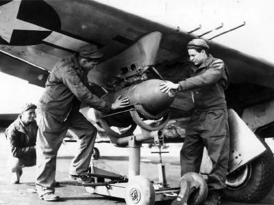Ground crew affix a 500 lb bomb to the underside of wing of a P-47 56th FG 1944