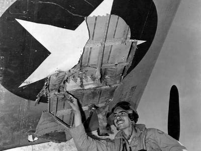 Lt John A. Dooling of 318th FG inspects hole made in the wing of his P-47 by AA fire