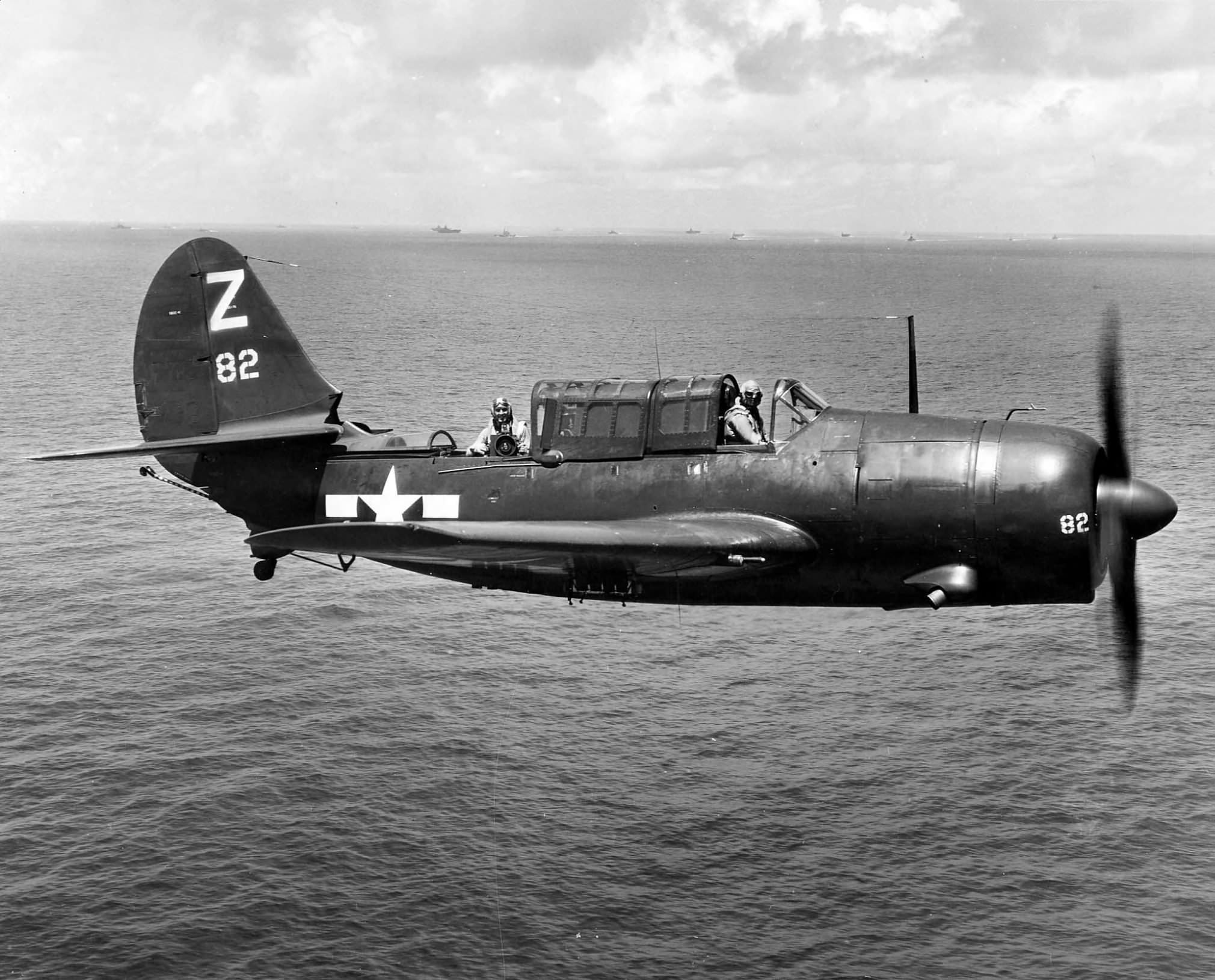 Curtiss SB2C-4E Helldiver ’82’ of VB-85 flies near TF 38 arrayed in the background on 17 August 1945