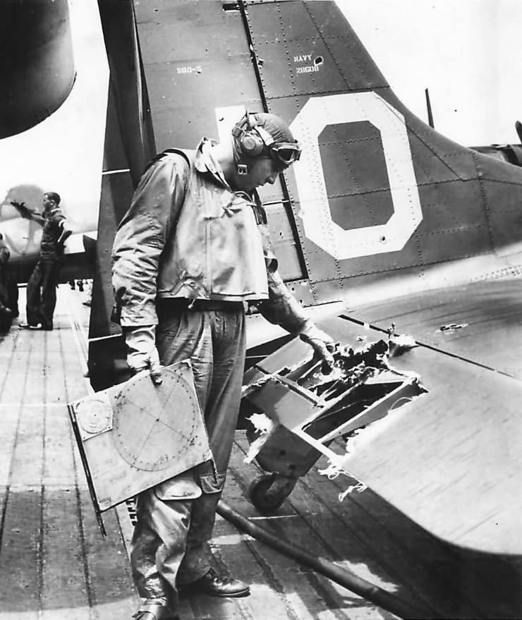 Lt. James K. Brothers of VB-9 inspects damage to his SBD-5 white 10 after returning safely to the aircraft carrier USS Essex following raid on Tarawa 1943