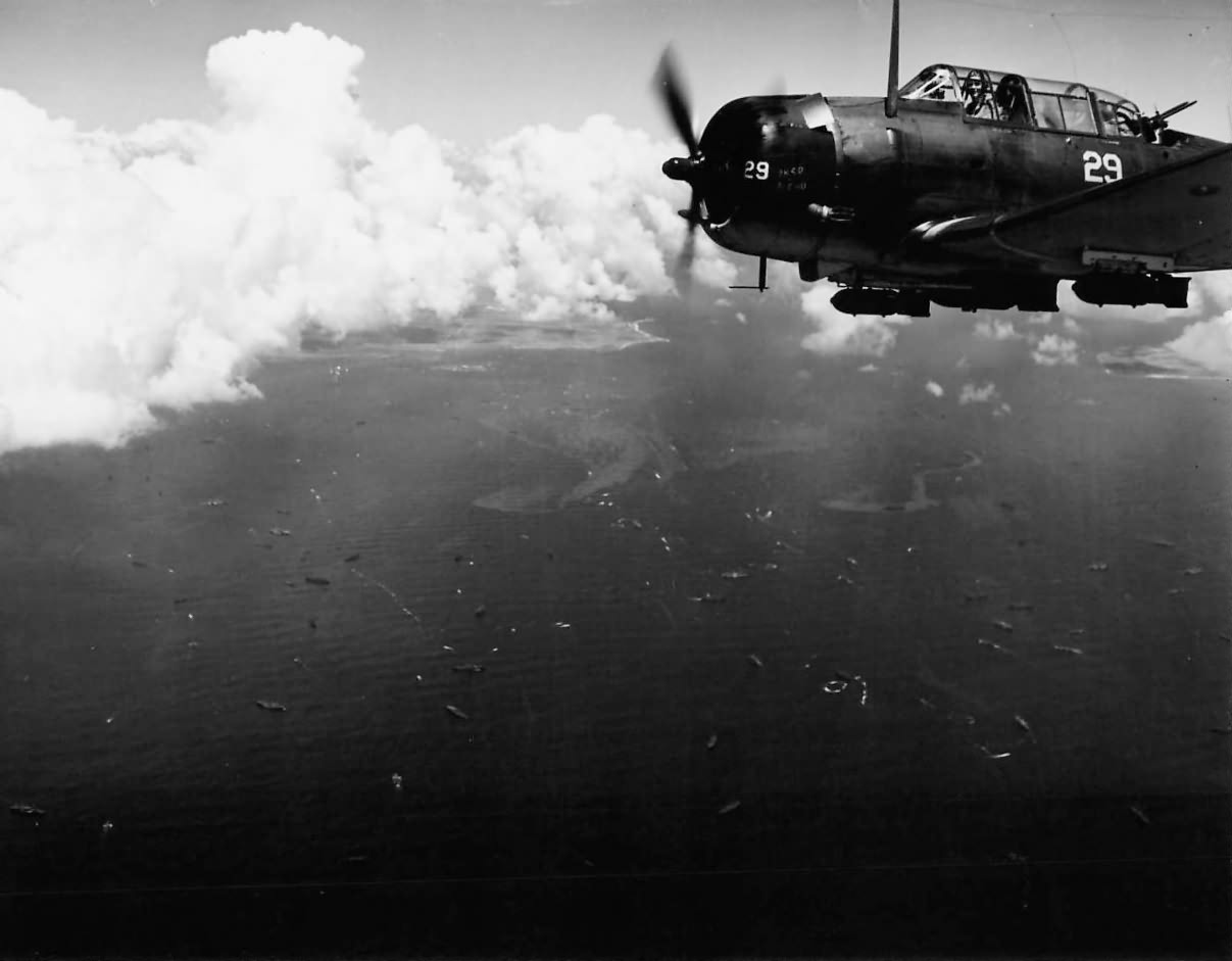 SBD-5 Dauntless white 29 from USS Lexington (CV-16) flies over inavsion craft off Saipan