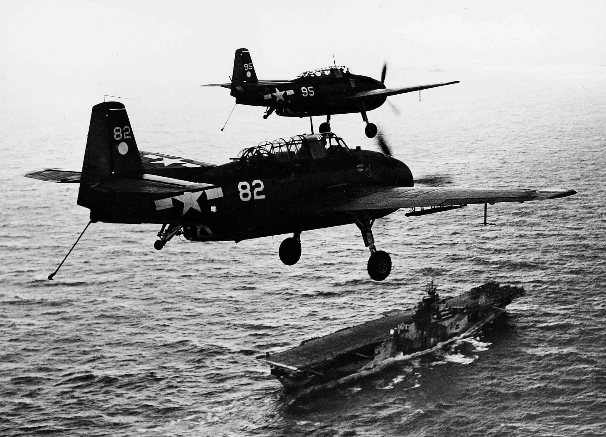 TBM-3 Avengers 82 and 95 of VT-2 with wheels and arrester hooks down above the carrier USS Hornet (CV-12) after a strike on Guam July 18 1944