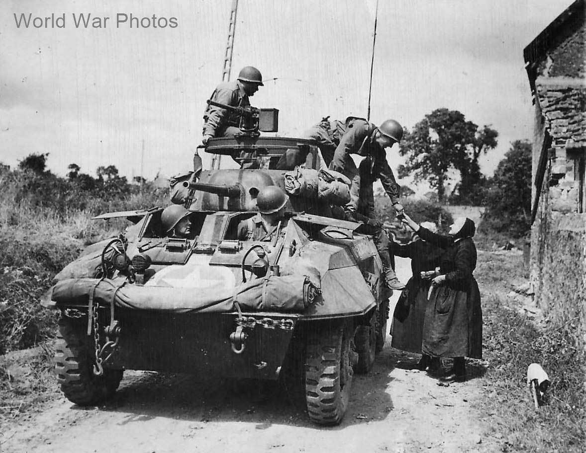 US Troops in M8 Greyhound stopped by hungry women in Periers 1944