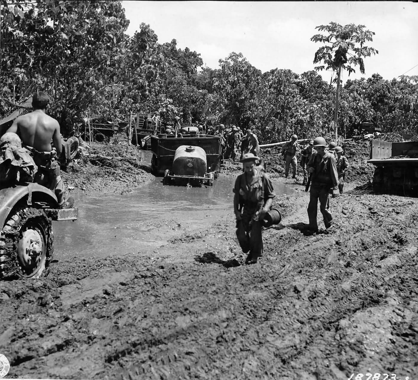 Soldiers and chained up trucks with trailer muddy road Bougainville 1944