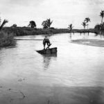 Marine uses a raft to cross a flooded road during the rainy season on Guadalcanal