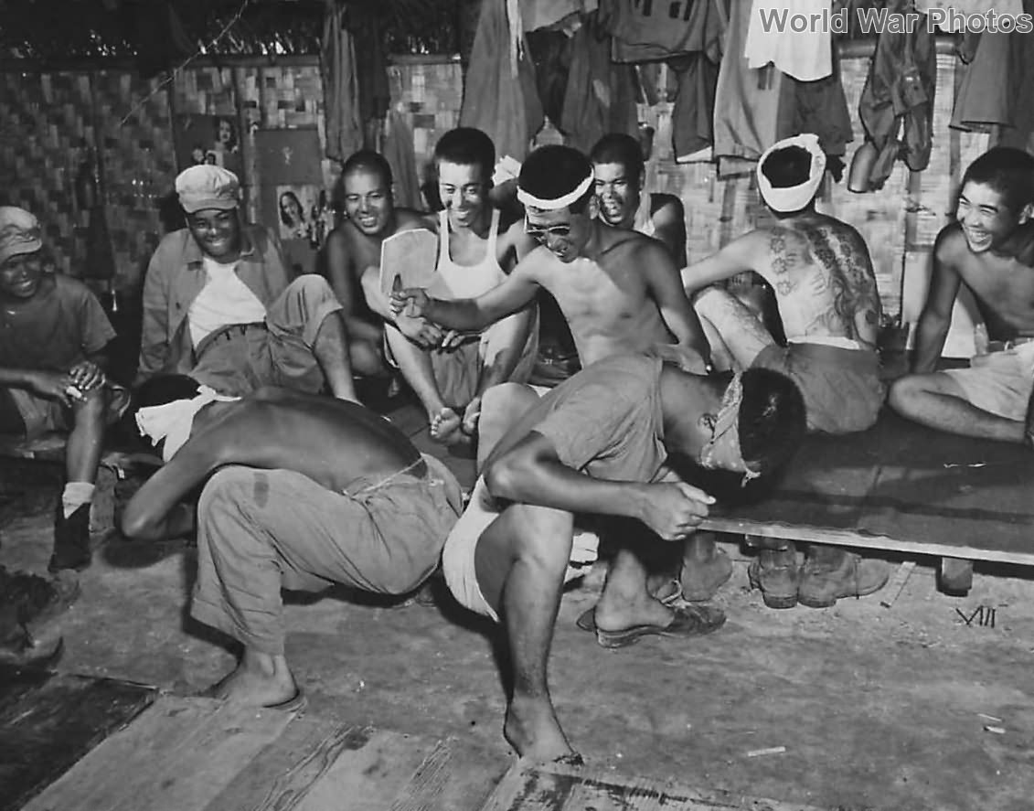 Japanese soldiers laugh as fellow prisoners play game on Guam 1945