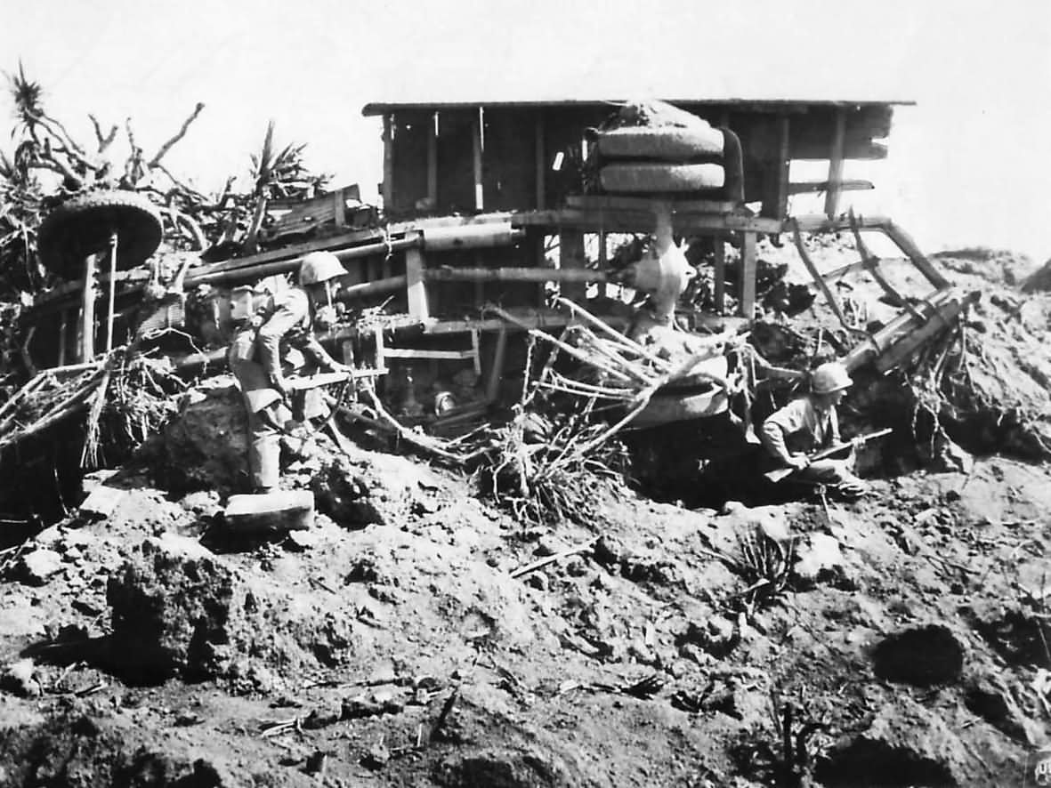 Marines take shelter behind an overturned Japanese truck