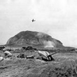 37 mm gun on Iwo Jima beach and Avenger flying over Mt Suribachi