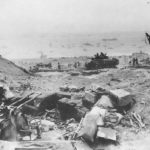 Troops on Iwo Jima Beach viewed over KO’d Japanese gun position