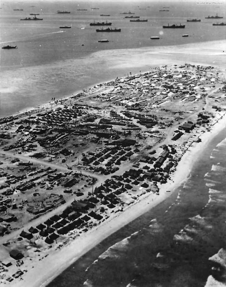 Aerial view of shell torn Kwajalein with US ships offshore 1944