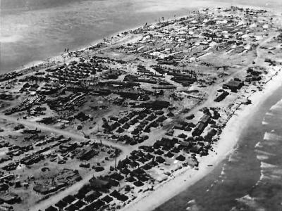 Aerial view of shell torn Kwajalein with US ships offshore 1944
