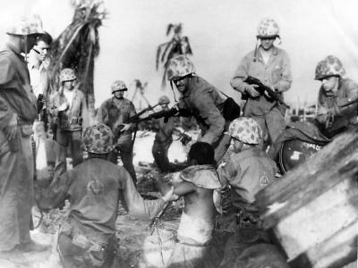 Marines of V Amphibious Corps pull an injured Japanese soldier from a bunker
