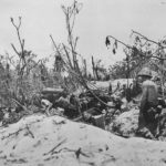 Marine with a carbine covers the entrance to a Japanese pillbox