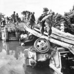 U.S. Troops use wrecked trucks to build bridge on Luzon