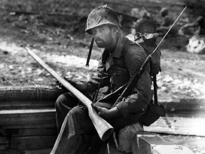 Marine examines a wooden dummy Japanese rifle used on Saipan