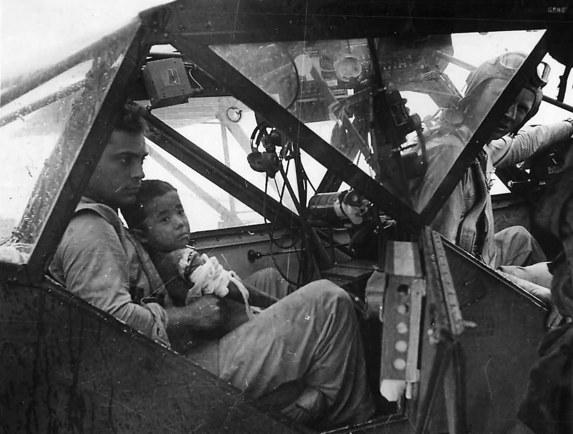 Soldier in L-5 Sentinel holds wounded boy before evacuation from Saipan
