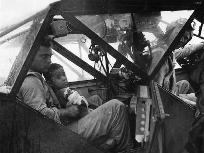 Soldier in L-5 Sentinel holds wounded boy before evacuation from Saipan