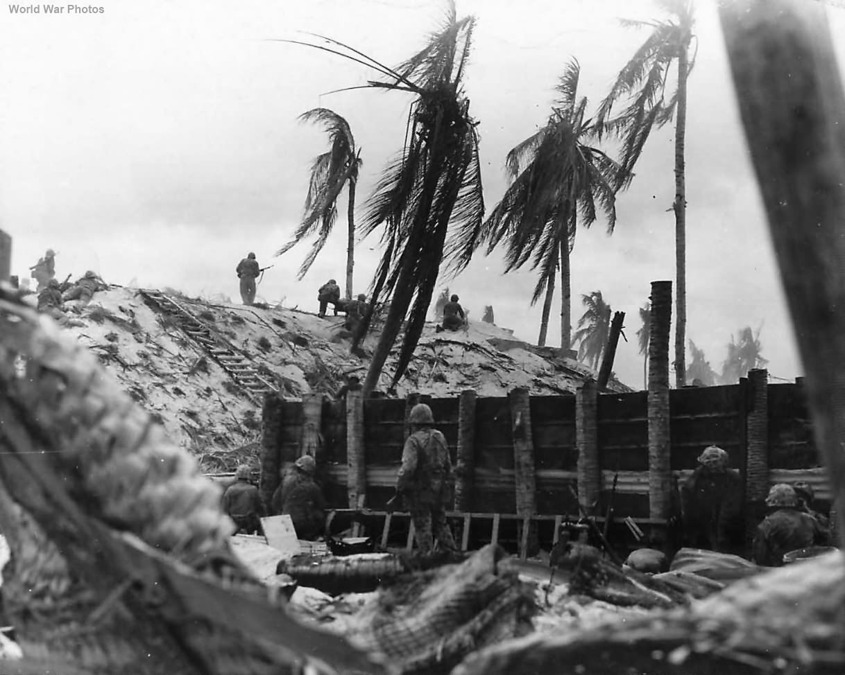 Marines swarm over high embankment on Beach of Tarawa