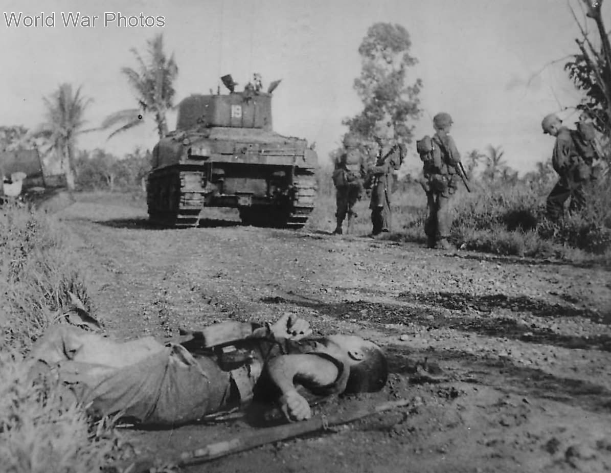 Sherman tank and U.S. troops pass fallen Japanese soldier during advance on Leyte