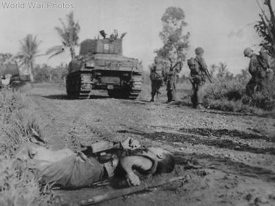 Sherman tank and U.S. troops pass fallen Japanese soldier during advance on Leyte