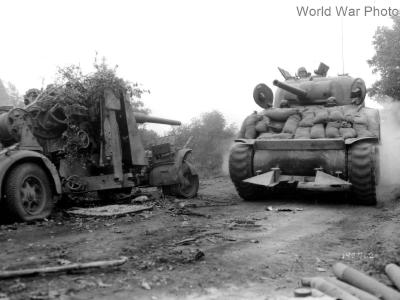 M4 tank with hedgerow cutter passing Flak 88 Normandy