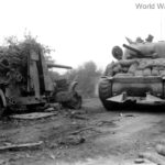 M4 tank with hedgerow cutter passing Flak 88 Normandy