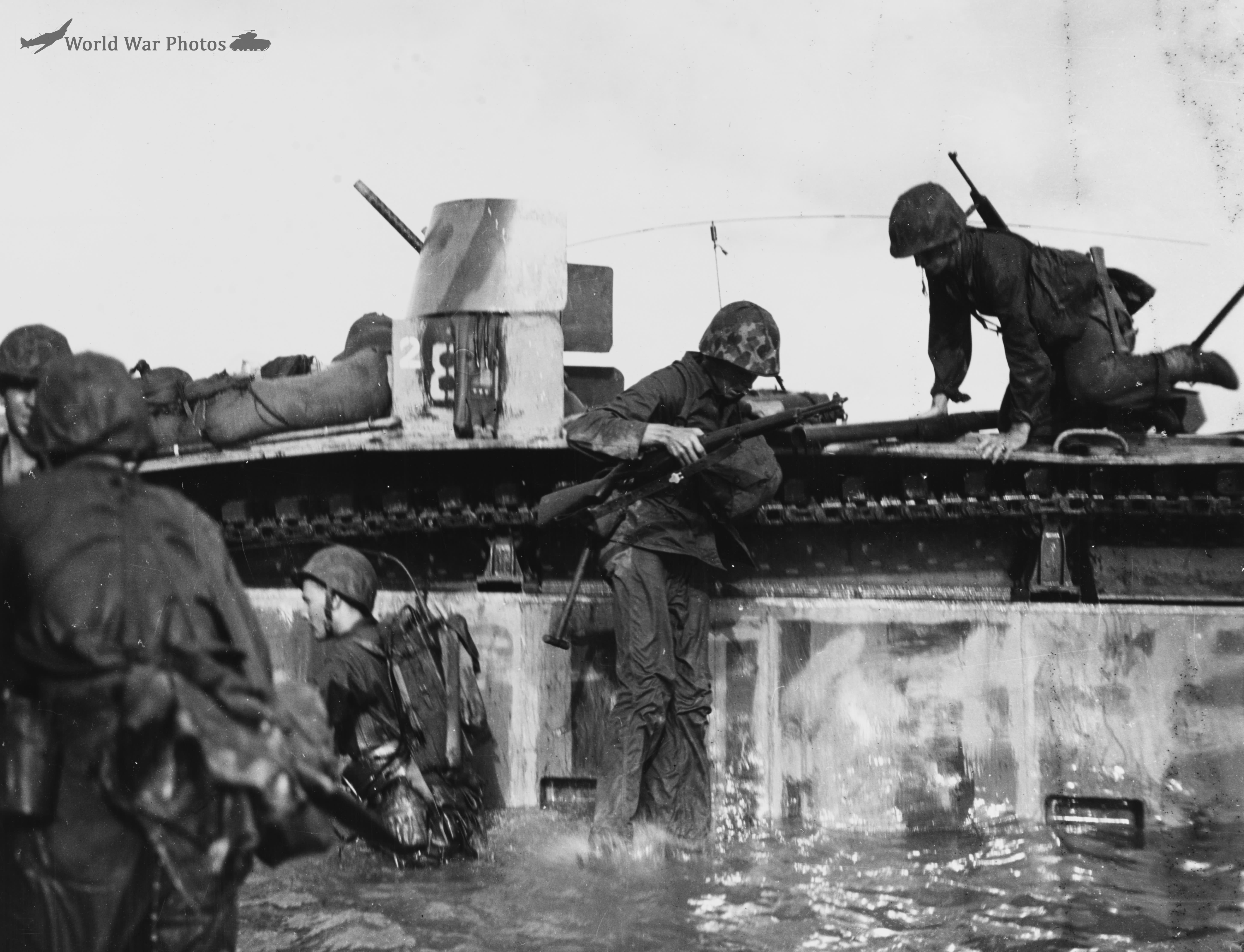 Marines demount from an LVT-2 at the Invasion beach at Tinian