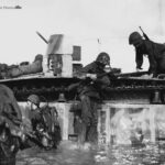 Marines demount from an LVT-2 at the Invasion beach at Tinian
