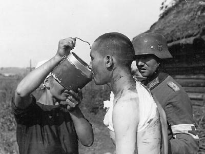 German medic and peasant give water to Russian POW