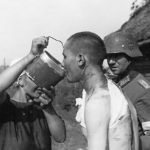 German medic and peasant give water to Russian POW